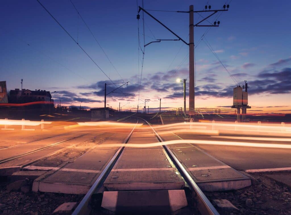 Railroad crossing with car lights in motion at night