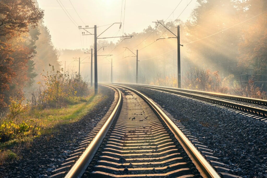 Railroad in beautiful forest in fog at sunrise in autumn